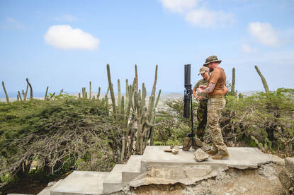 Radiozendmast op een Arubaanse heuveltop met twee militairen.