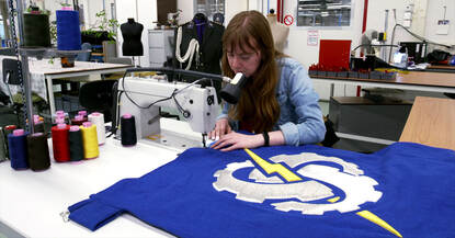 Kleermaker werkt met een naaimachine aan de nieuwe eenheidsvlag van COMMIT.