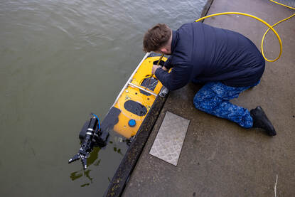 Een medewerker van de koninklijke marine legt Anti-IED Security Platform Sea Wasp in het water.