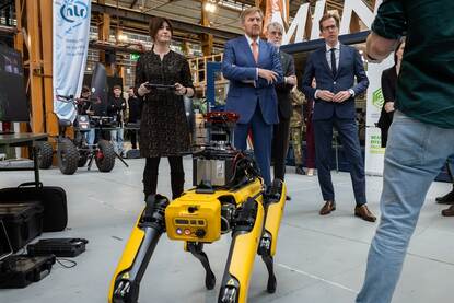 Koning Willem Alexander en staatssecretaris Van der Maat kijken naar een demonstratie met een robothond.