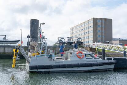 USV90 aan de kant in de marinehaven Den Helder met een onderwaterdrone aan een soort kraan aan de achterzijde.