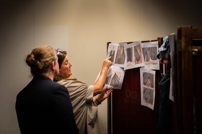 Medewerker leverancier wijst naar een foto van het jasje naast enkele andere voorbeeldfoto's.