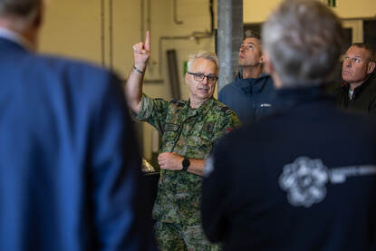 Sergeant-majoor Dave binnen een groep mensen wijst naar boven en mensen kijken naar boven.