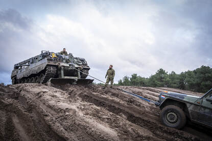 Bergingstank op heuvel met lierkabel aan MB-terreinwagen onderaan heuvel.