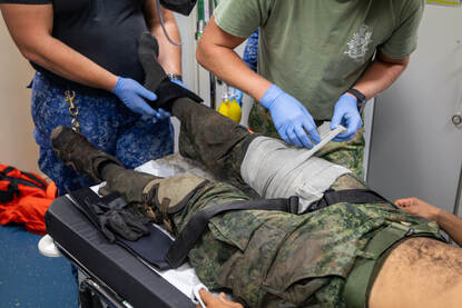 Vier foto’s met een vlootcollega die op een bootjes schiet, een gewonde marinier die medisch wordt geholpen en collega’s aan het werk in de kombuis.